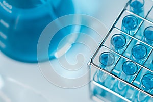 Test tubes and erlenmeyer flask filled with blue sample chemicals in chemistry science laboratory. Glassware in medical research.