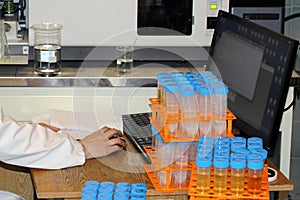 Engineer ecologist analyzes the computer. Test tubes with samples of soil, water and air in a real environmental laboratory.