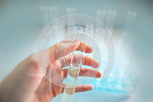 Test tubes are seen through protective goggles in a biology lab, hand holding transparent plastic glasses