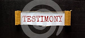 Testimony symbol. The word `Testimony` appearing behind torn black paper. Beautiful black background. Business, testimony concep