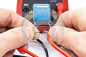 Testing capacitor with multimeter on a white background