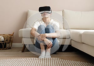 Testing new technologies. Attractive young woman in VR headset gesturing and smiling while sitting at home