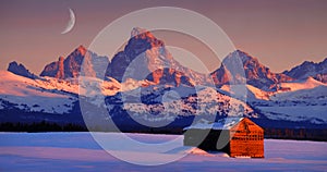 Tetons Mountains at Sunset in Winter with Old Cabin Homestead Building and Rising Cresent Moon