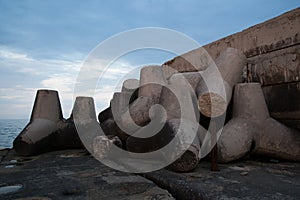 Tetrapod breakwaters lie on the shore near the sea. Tetrapod stones, close-up. Concrete tetrapods for protect coastal structures