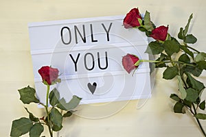 Tex Only you written on a lightbox with roses.