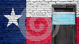 Texas flag painted on brick wall and closed door with medical mask protected