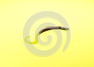 Texas rig with bullet sinker, glowing plastic worm and offset worm hook isolated on yellow background