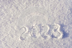 Text 2023 written on white fresh sparkling snow on sunny winter day. Merry Christmas and Happy New Year. Winter holiday concept.