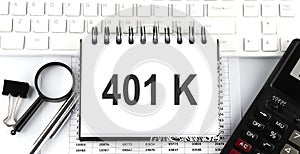 Text 401K on notebook . Keyboard, diagram and white background