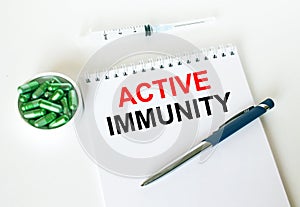 Text Active Immunity written in a notebook with a blue pen and a bunch of pills