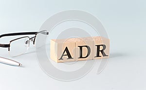 Text ADR - written on the wooden cubes on blue background