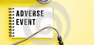 Text ADVERSE EVENT on notebook with stethoscope on yellow background.