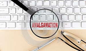 Text AMALGAMATION on keyboard with magnifier , glasses and pen on beige background