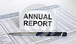 Text Annual Report on white card with blue metal pen on financial table