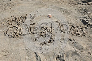 Text ANY QUESTIONS writte on the sand of beach