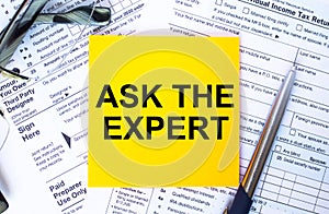 Text Ask The Expert on note paper with the U.S IRS 1040 form,pen and glasses