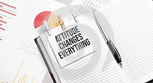 text Attitude Changes Everything on stickers on the diary with office tools