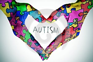 Text autism and hands forming a heart with puzzle pieces photo