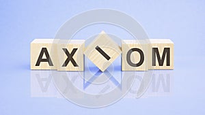 text AXIOM - letters by on woodens blocks on pale lilac background, in concept of business and corporation