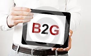 Text B2G on tablet display in businessman hands on the white bakcground. Business concept