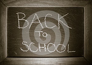 Text back to school concept written on chalkboard with wooden frame