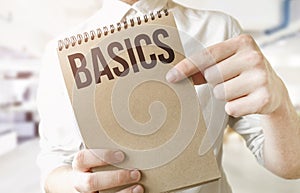 Text BASICS on brown paper notepad in businessman hands in office. Business concept