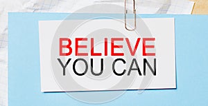 Text Believe you can on a white card on a blue background. Business concept