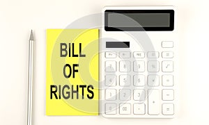 Text BILL OF RIGHTS on yellow sticker, next to pen and calculator