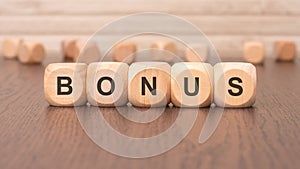 the text 'bonus' is written on wooden cubes on a brown background