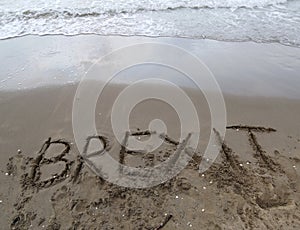 Text BREXIT on the sand of the sea waiting to be erased by the w