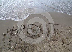 Text BREXIT on the sand of the sea waiting to be erased by the w