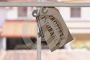 Text on brown paper and key hanging on the window grill with blurred background of houses