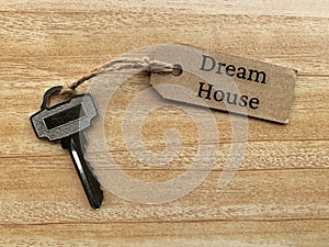 Text on brown tag with house key and wooden table background - Dream house. Property concept.