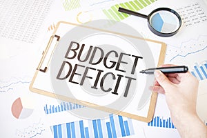 Text budget deficit on white paper sheet and marker on businessman hand on the diagram. Business concept