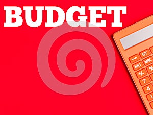 Text BUDGET on red background with orange calculator. photo