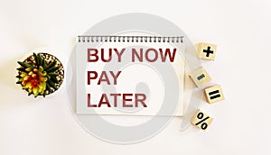 Text buy now pay later on notepad and white background. Cubes with zakami plus, minus, equals