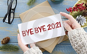 Bye Bye 2021 on white paper on red Christmas background. Farewell to 2021 concept