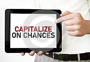 Text CAPITALIZE ON CHANCES on tablet display in businessman hands on the white background. Business concept