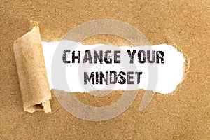 The text CHANGE YOUR MINDSET appearing behind torn brown paper