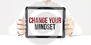 Text Change Your Mindset on tablet display in businessman hands on the white bakcground. Business concept