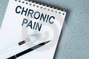 The text is a chronic pain. Top view written on white paper pad on the desktop. Medical concept