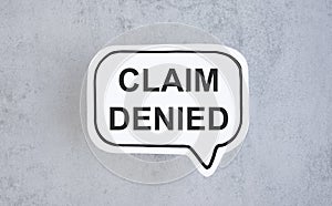 Text CLAIM DENIED On a white card on a gray