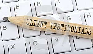 Text Client testimonials on wooden pencil on white keyboard. Business concept