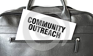 Text COMMUNITY OUTREACH writing on white paper sheet in the black business bag. Business concept