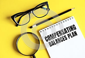 Text Compensating Balances Plan written on a notebook with glasses, magnifying glass and pencil