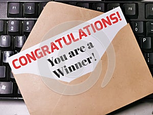 Text CONGRATULATIONS YOU ARE A WINNER written on white paper note in the envelope