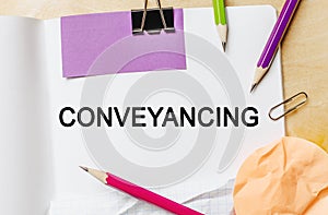 Text Conveyancing on a white note background with pencils, stickers and paper clips. Business concept