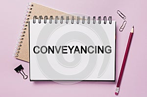 Text Conveyancing on a white notepad with office stationery background. Flat lay on business, finance and development concept