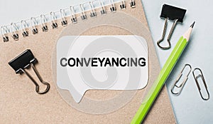 Text Conveyancing on a white sticker with office stationery background. Flat lay on business, finance and development concept