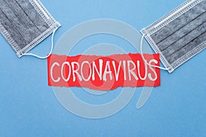 Text CORONAVIRUS on blue background and gray protect face mask with copy space. Global novel coronavirus Covid-19 outbreak